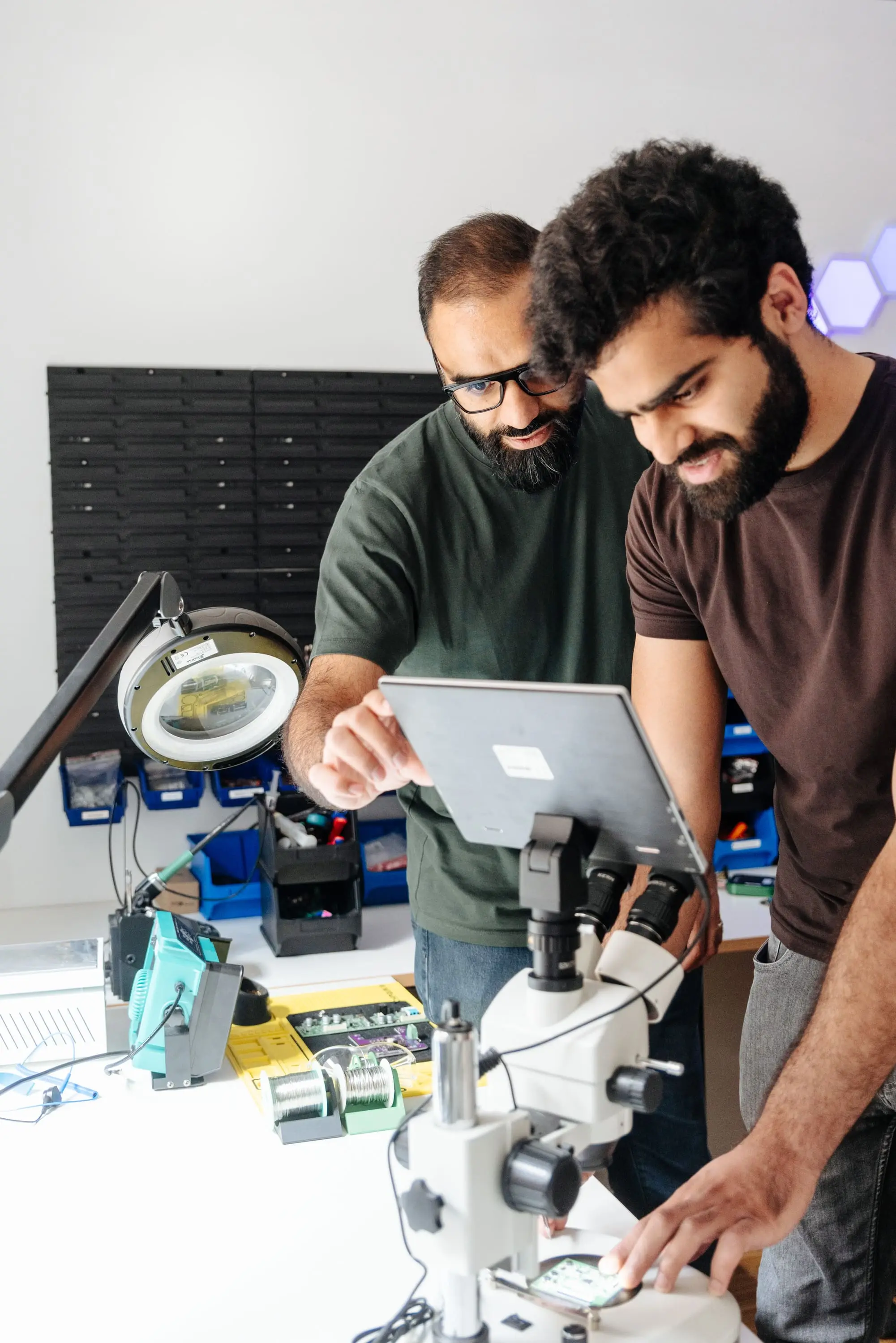 Two Better Devices engineers examining a board under a microscope