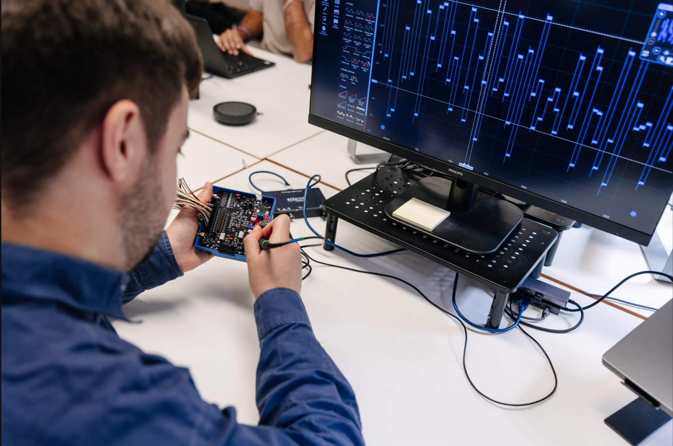 An engineer probing a board while decoding its protocol on a logic analyser